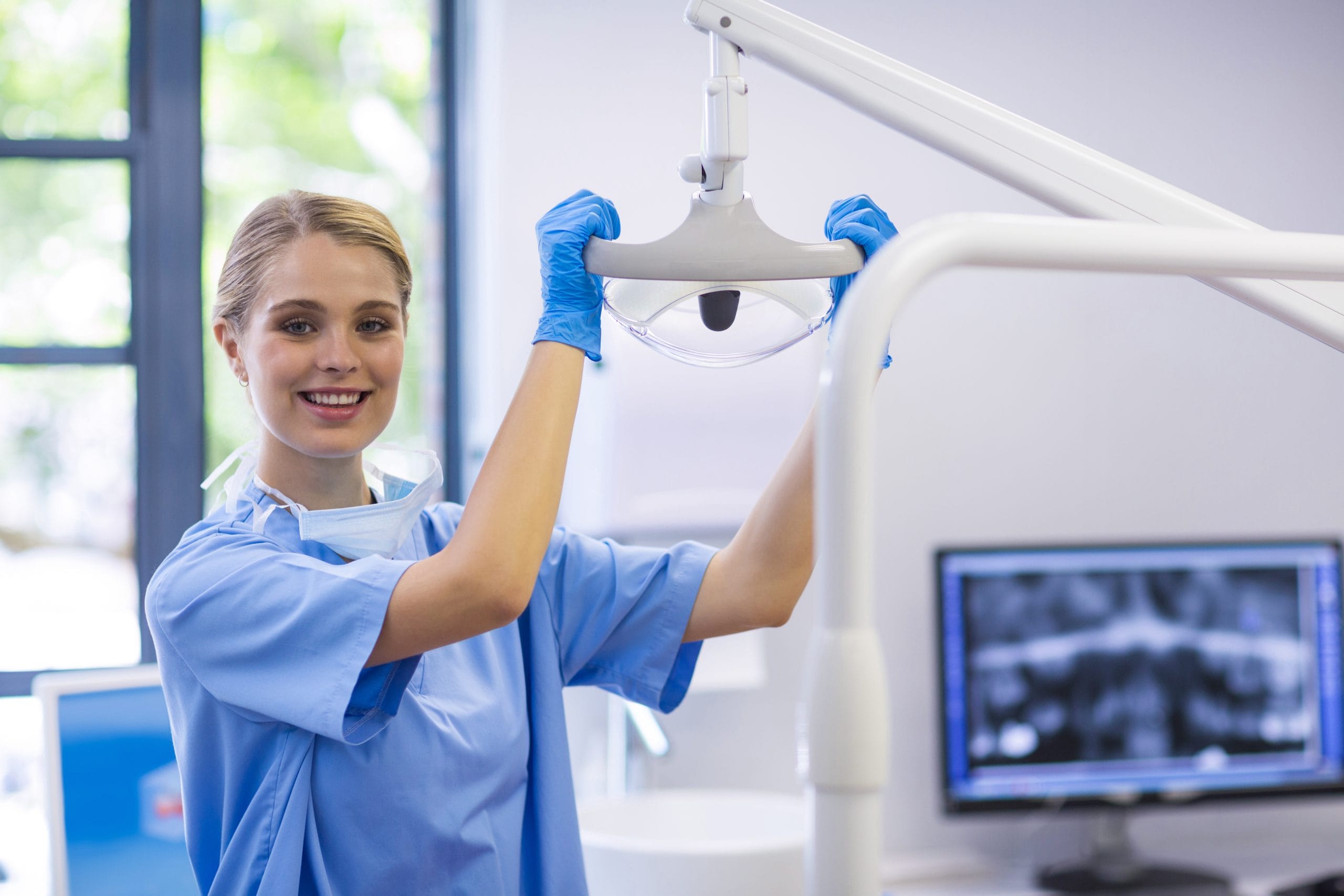Young female dental nurse apprentice moving dental light in a dental practice